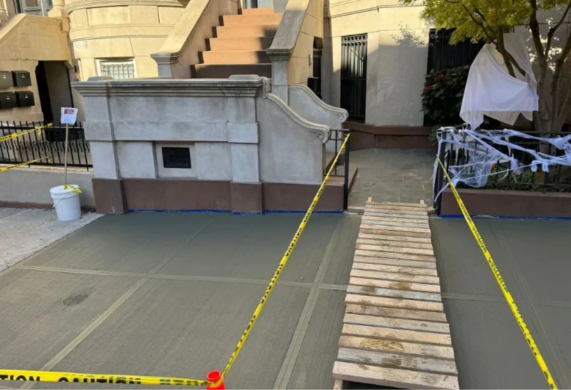 Concrete sidewalk in Queens, displaying a strong and smooth surface that blends with the surrounding urban landscape.